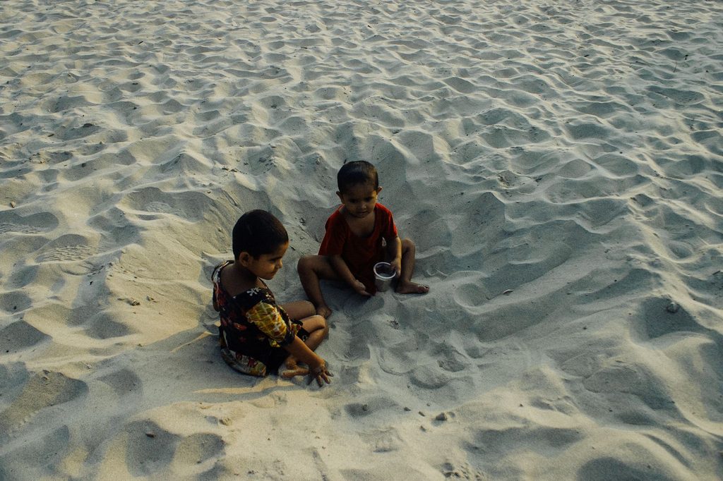 Happy kids playing with sand on beach